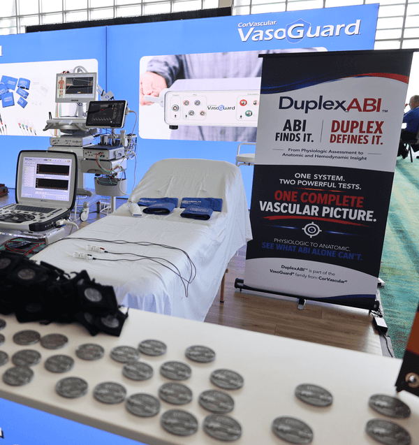 The DuplexABI demo station and commemorative coin table at the CorVascular booth, SVU 2026