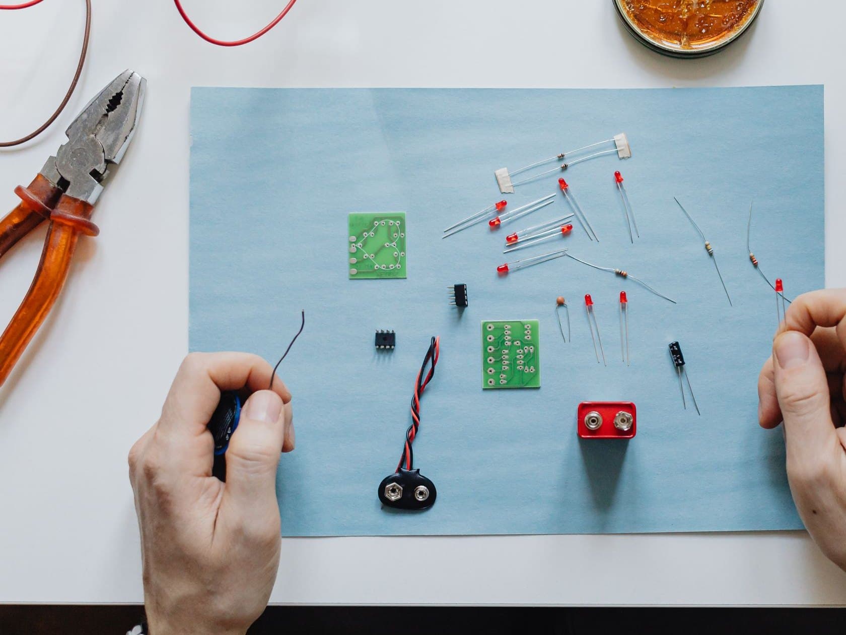 Overhead view of hands working through electronic components on a bench mat